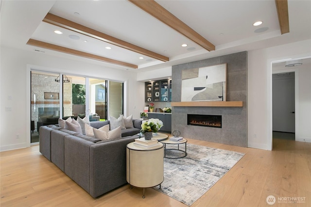 living area with a tiled fireplace, wood finished floors, baseboards, beamed ceiling, and recessed lighting