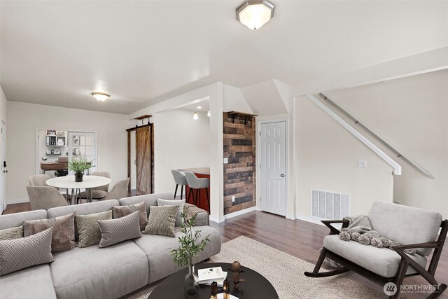 living area with baseboards, visible vents, a barn door, and wood finished floors