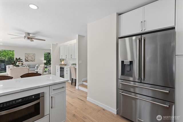 1825 112th Ave NE, Bellevue, WA 98004 - kitchen featuring baseboards, light stone counters, white cabinetry, wine cooler, and high quality fridge