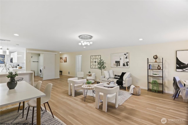 living area featuring washer / dryer, recessed lighting, light wood-style floors, and baseboards