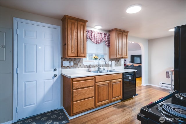 kitchen featuring arched walkways, a sink, black appliances, and decorative backsplash
