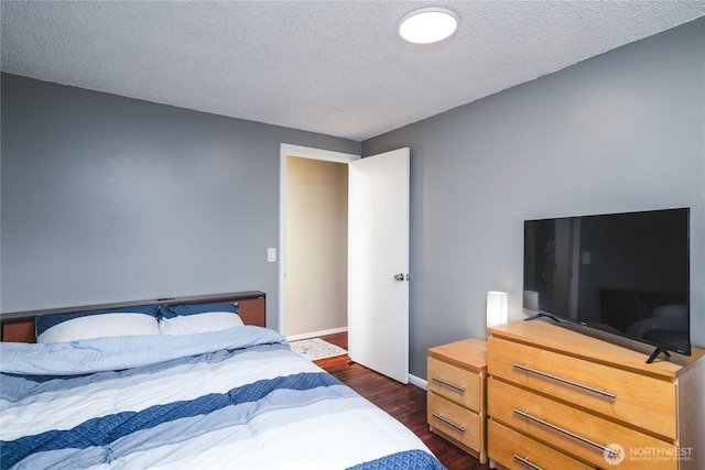 bedroom featuring dark wood-type flooring, baseboards, and a textured ceiling