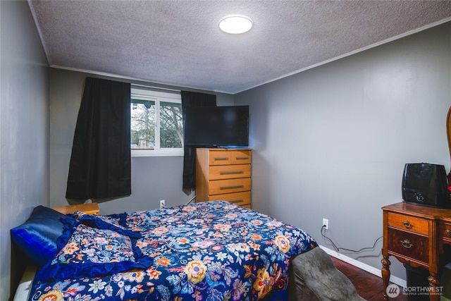 bedroom with baseboards, a textured ceiling, crown molding, and wood finished floors