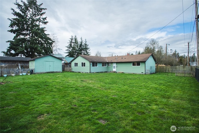 rear view of property featuring a yard, a fenced backyard, an outdoor structure, and a storage unit