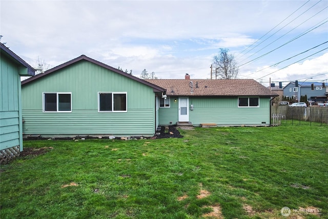 back of property featuring fence and a lawn