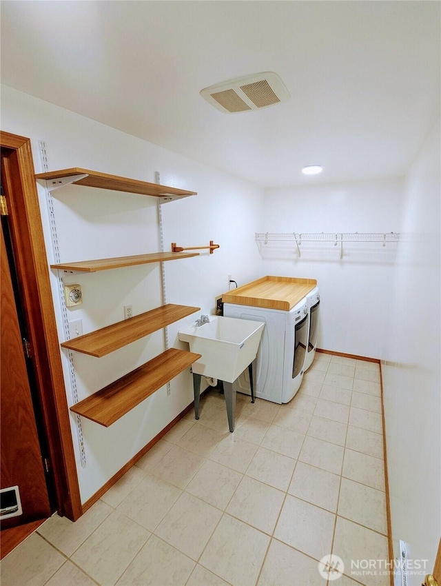 laundry area with visible vents, washing machine and clothes dryer, laundry area, and light tile patterned floors