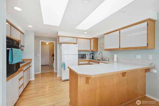 858 Livingston Bay Shore Dr, Camano Island, WA 98282 - kitchen with a skylight, oven, a peninsula, a sink, and freestanding refrigerator