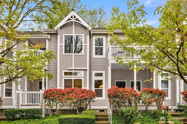 rear view of house with a balcony and stucco siding
