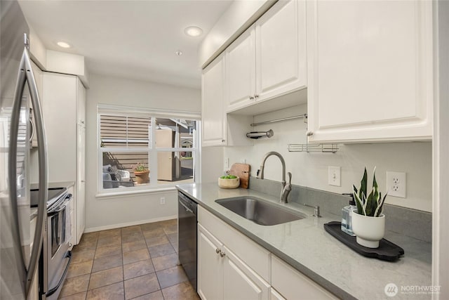 kitchen featuring appliances with stainless steel finishes, a sink, white cabinetry, baseboards, and recessed lighting