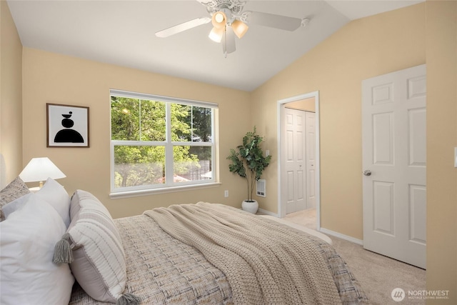 bedroom featuring ceiling fan, vaulted ceiling, baseboards, a closet, and light carpet