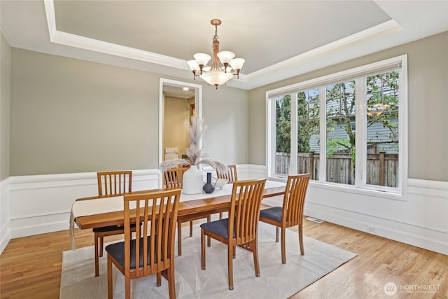 2070 277th Ave SE, Sammamish, WA 98075 - dining room featuring a raised ceiling, a chandelier, a wainscoted wall, light wood finished floors, and ornamental molding