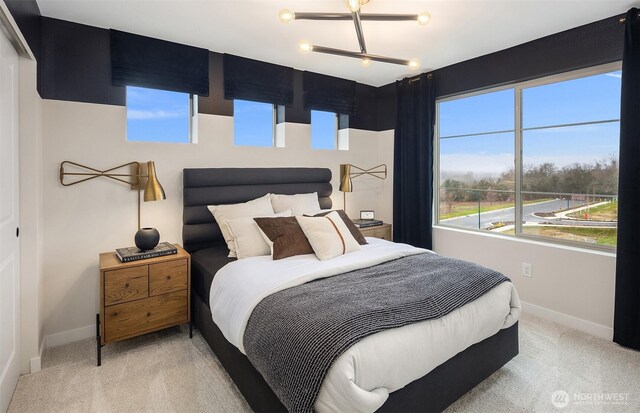 bedroom with baseboards and light colored carpet