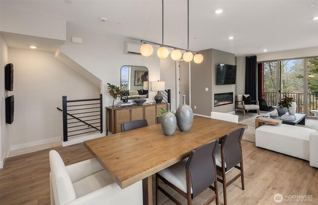 dining space with a glass covered fireplace, recessed lighting, light wood-type flooring, and baseboards