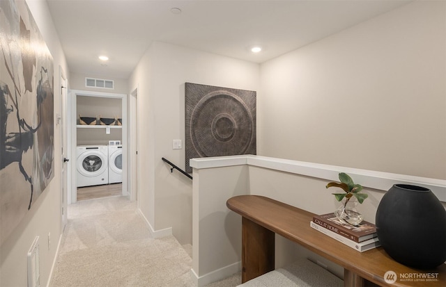 hall featuring visible vents, an upstairs landing, washer and clothes dryer, carpet flooring, and baseboards