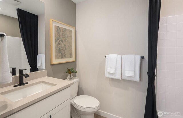 bathroom with curtained shower, toilet, and vanity