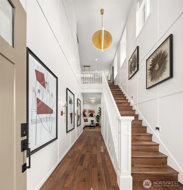 foyer entrance with stairway, dark wood-type flooring, and a towering ceiling