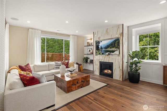 living room with recessed lighting, wood finished floors, visible vents, and a premium fireplace
