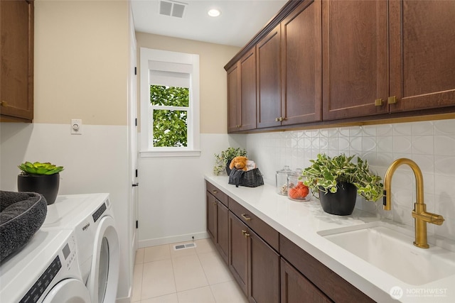 laundry room featuring cabinet space, washing machine and dryer, visible vents, and a sink