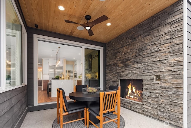 view of patio / terrace featuring outdoor dining space, an outdoor stone fireplace, and a ceiling fan