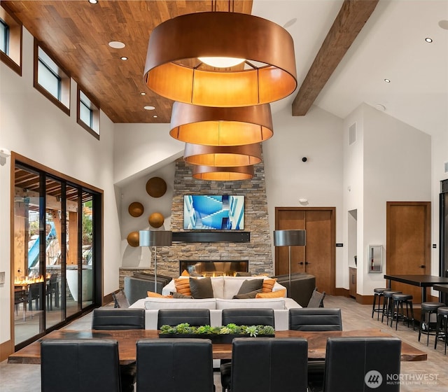 dining area with beamed ceiling, plenty of natural light, high vaulted ceiling, and a fireplace