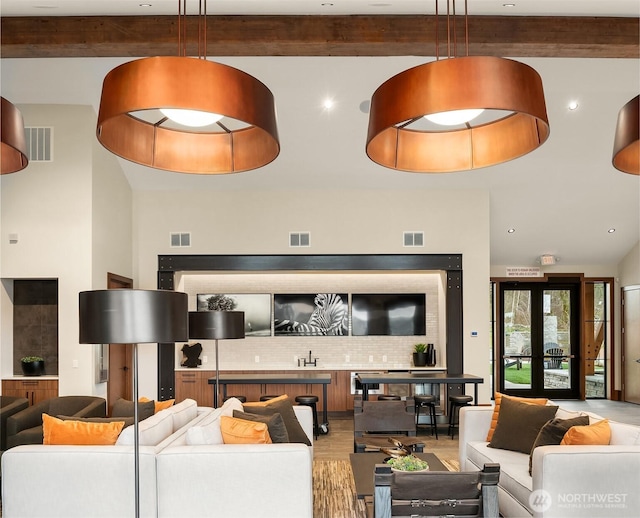living area featuring beam ceiling and visible vents