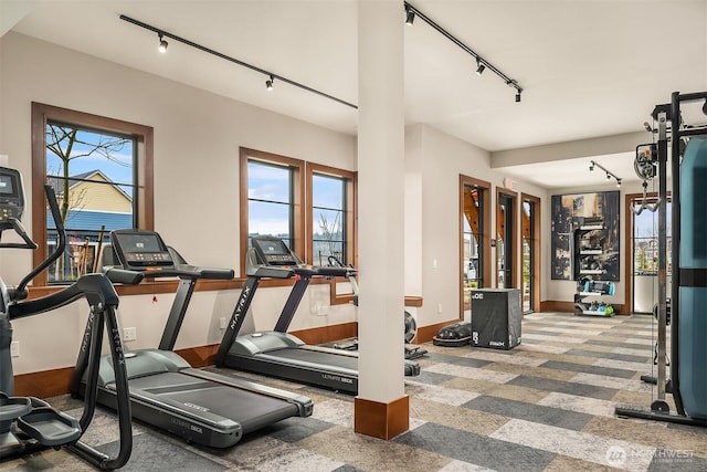 interior space with rail lighting, carpet, and baseboards