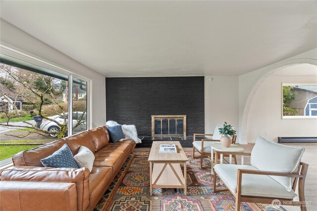 1309 W 5th St, Aberdeen, WA 98520 - living area with wood finished floors, arched walkways, a fireplace, and baseboard heating