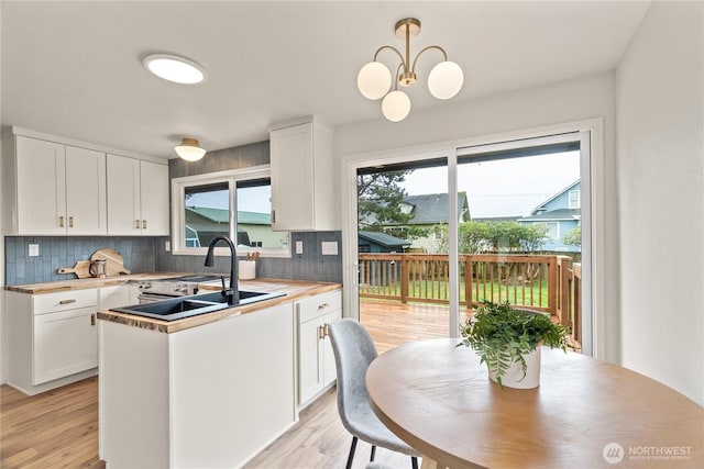 1309 W 5th St, Aberdeen, WA 98520 - kitchen featuring decorative backsplash, a chandelier, white cabinetry, a sink, and light wood-type flooring