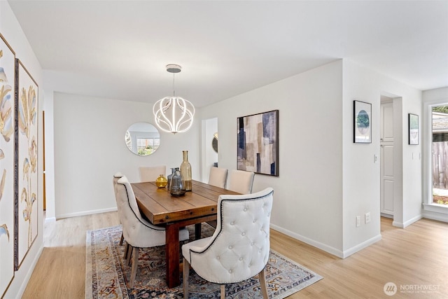 dining area with a chandelier, light wood finished floors, and baseboards