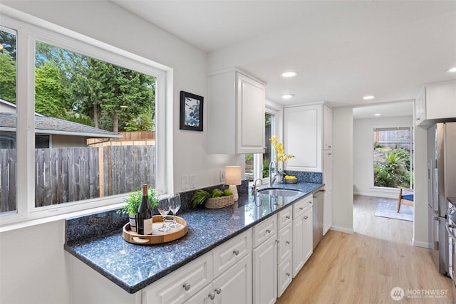 kitchen featuring a sink, dishwasher, light wood-type flooring, white cabinetry, and recessed lighting