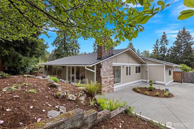 view of front of house featuring a chimney, fence, a sunroom, a shingled roof, and a gate