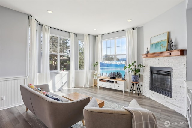 living area with wood finished floors, a fireplace, wainscoting, and recessed lighting