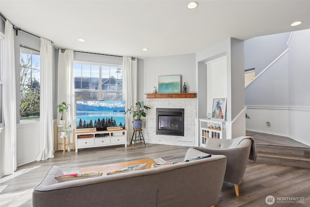 living area featuring wood finished floors, a fireplace, stairs, and recessed lighting