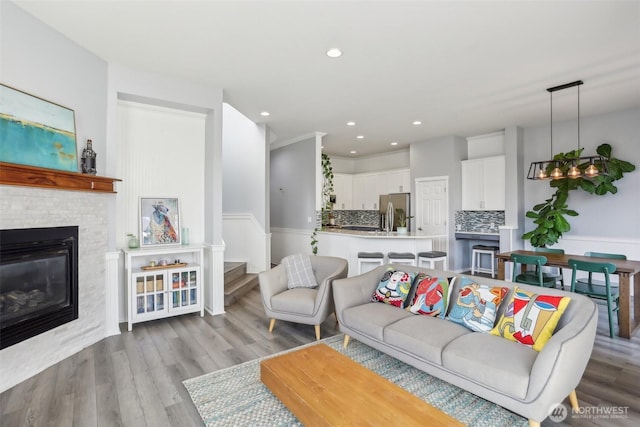 living area featuring recessed lighting, wood finished floors, wainscoting, and a glass covered fireplace