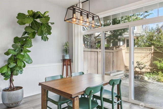 dining room featuring wood finished floors, an inviting chandelier, and wainscoting