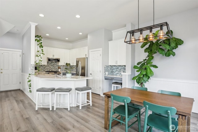 kitchen featuring tasteful backsplash, appliances with stainless steel finishes, light countertops, and a peninsula