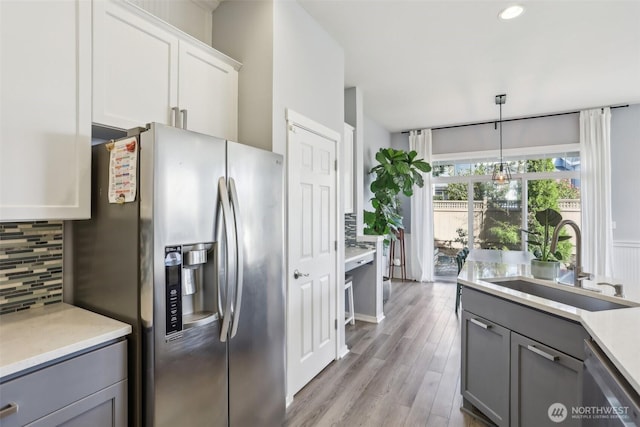 kitchen featuring tasteful backsplash, gray cabinets, light countertops, appliances with stainless steel finishes, and a sink