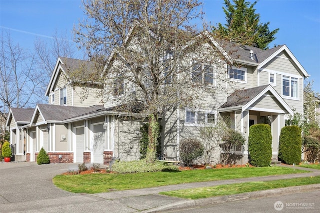 view of front of home featuring an attached garage, aphalt driveway, roof with shingles, and a front lawn