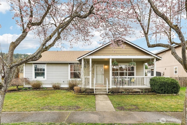 view of front of property featuring a porch, roof with shingles, and a front lawn