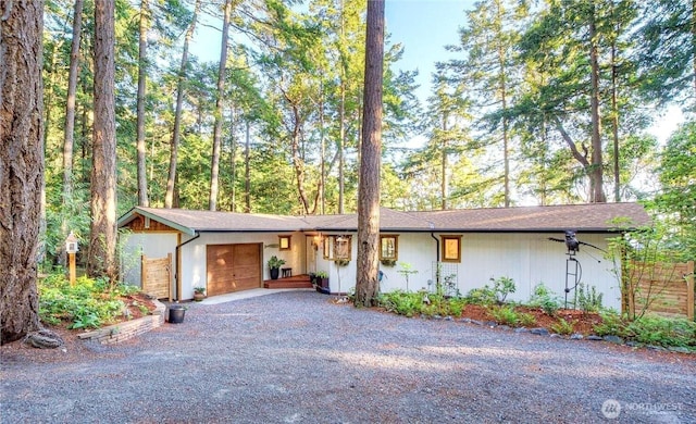 single story home with an attached garage and gravel driveway