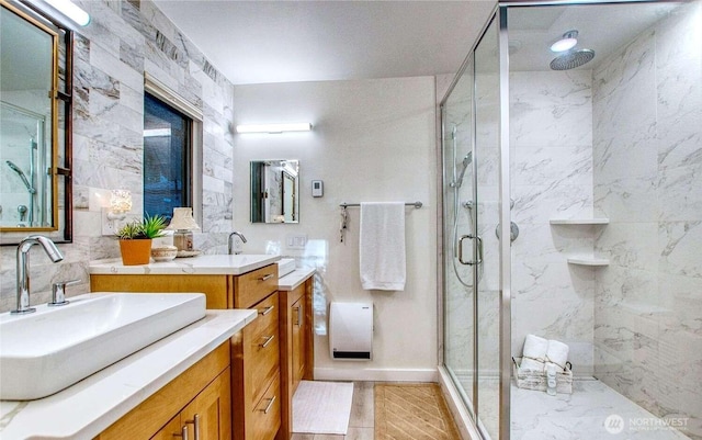 full bathroom with two vanities, a sink, and a marble finish shower