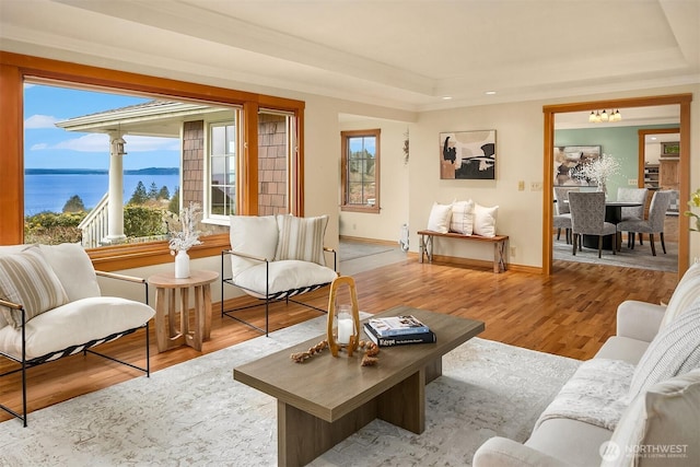 living room with a raised ceiling, crown molding, wood finished floors, and baseboards