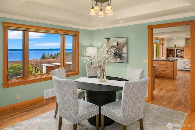 dining area with visible vents, a tray ceiling, an inviting chandelier, and wood finished floors