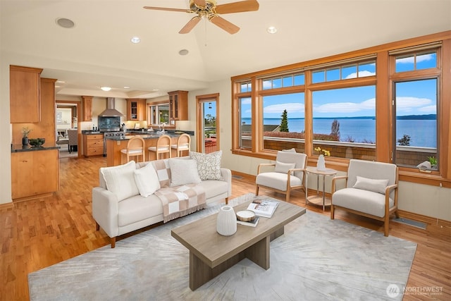 living room featuring a healthy amount of sunlight, light wood-type flooring, a ceiling fan, and lofted ceiling