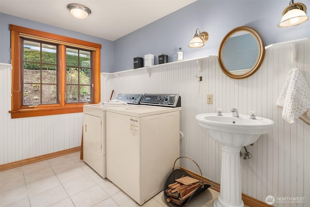 laundry area featuring washer and clothes dryer, laundry area, a wainscoted wall, and light tile patterned flooring