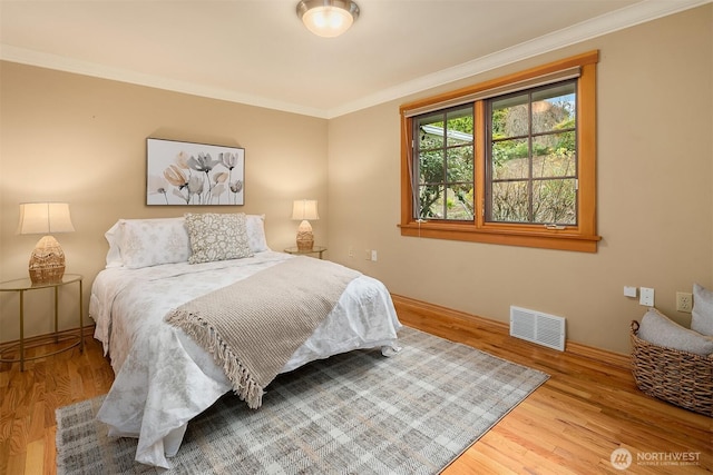bedroom featuring crown molding, wood finished floors, and visible vents