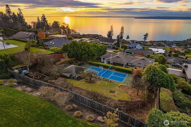 aerial view at dusk featuring a water view and a residential view