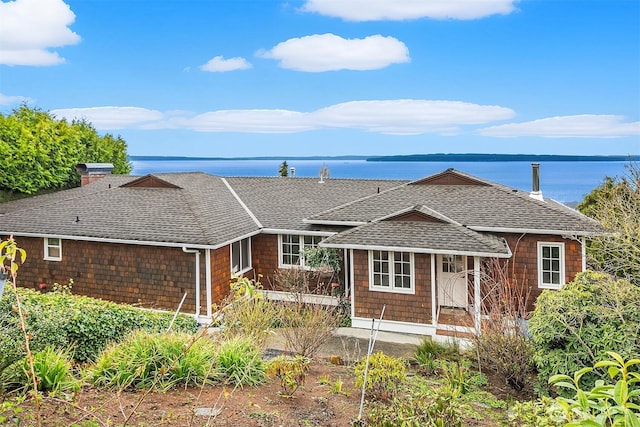 view of front of property featuring a chimney, a shingled roof, and a water view