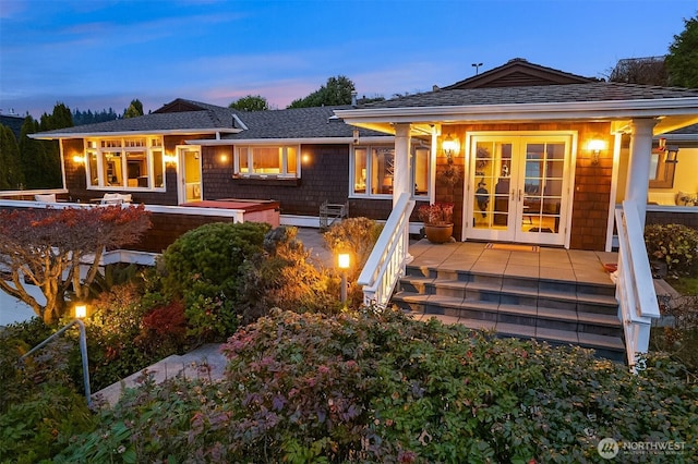 back of house at dusk featuring french doors