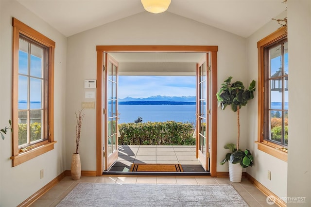 entryway featuring tile patterned floors, a water and mountain view, vaulted ceiling, and a healthy amount of sunlight